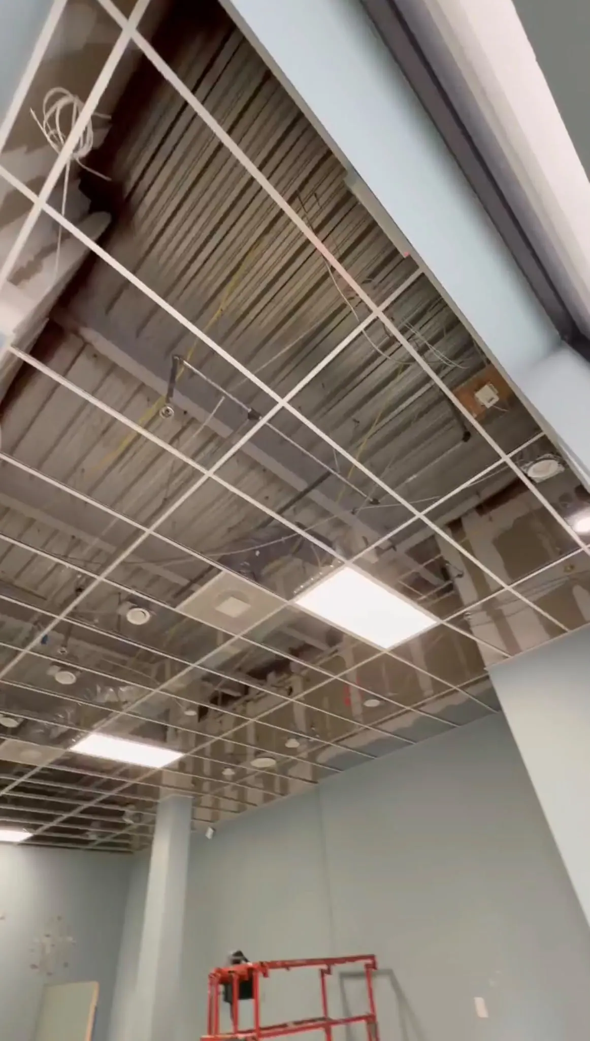 Open ceiling grid with ductwork and diffusers exposed during the work